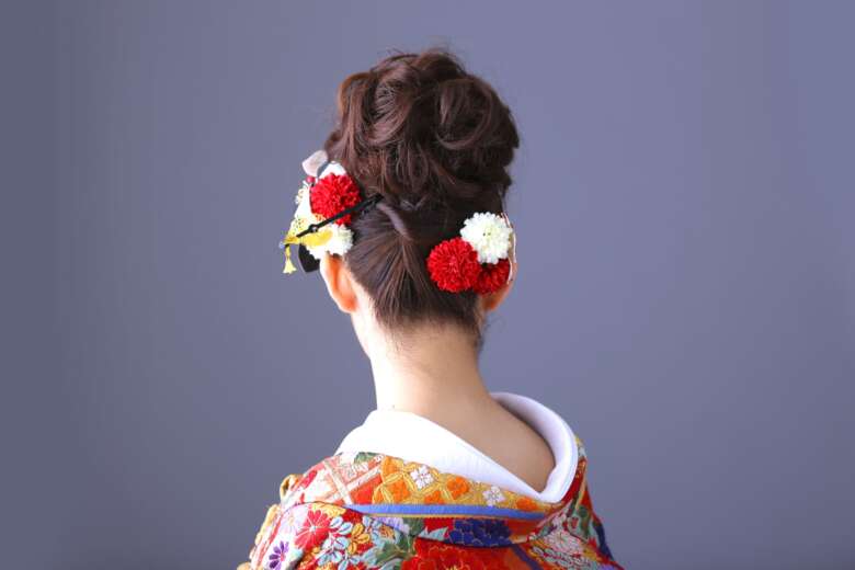 花の髪飾りをつけた洋髪の女性の後ろ姿